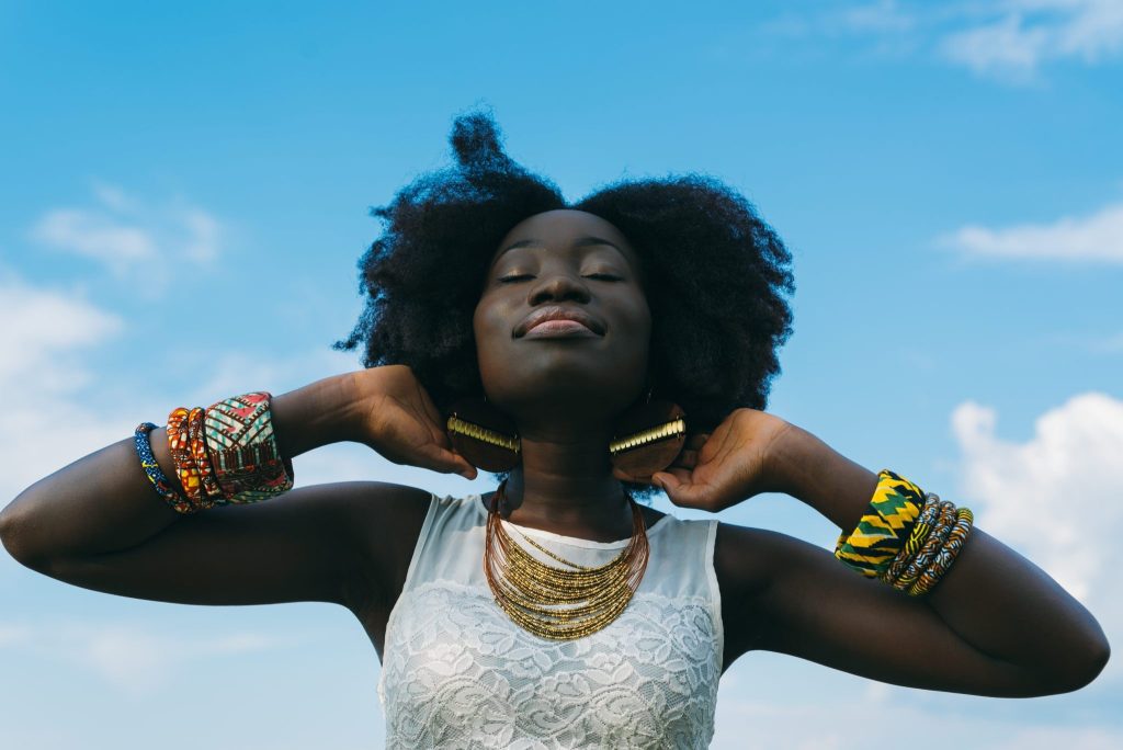 Mujer negra afro sonriendo hacia el cielo