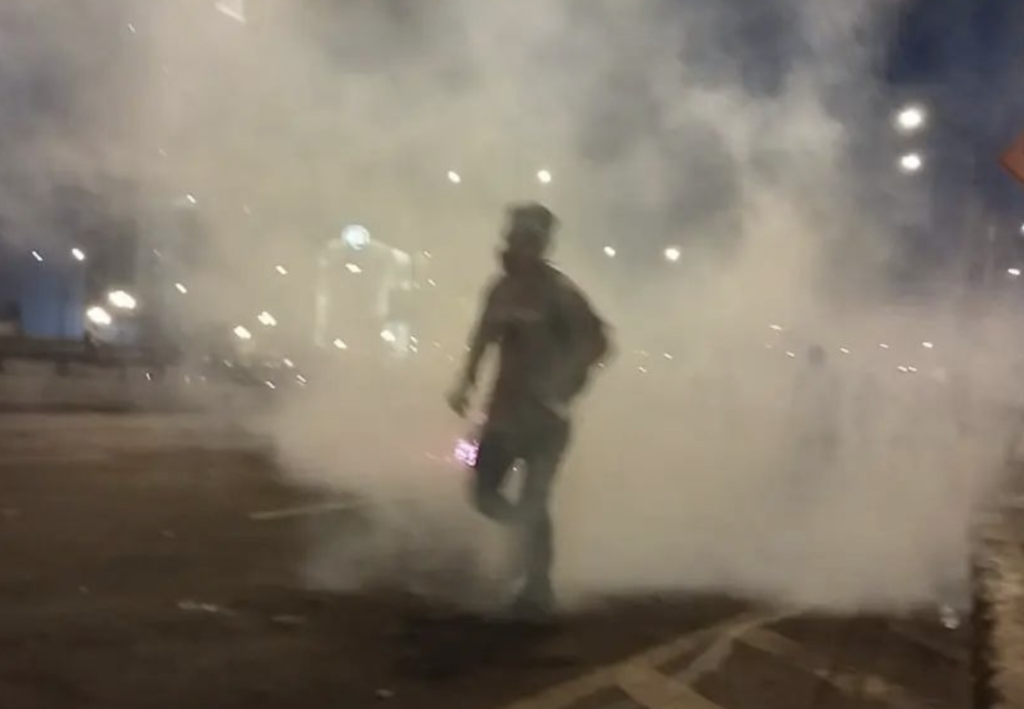 manifestante peruano entre el humo lagrimógeno camina.