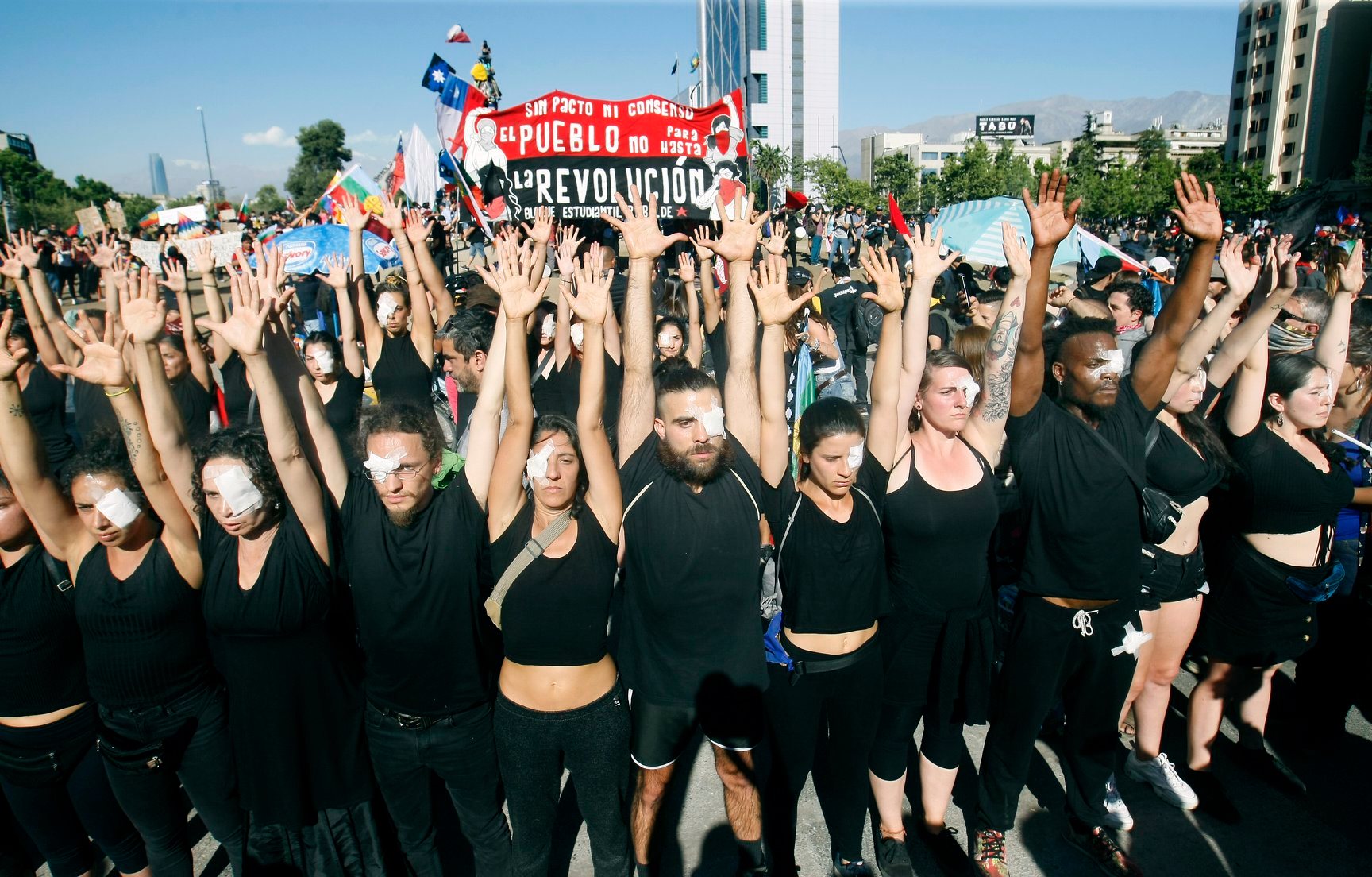 Jóvenes vestidos de negro y con parches en los ojos protestando por personas con traumas oculares en la Plaza Dignidad.